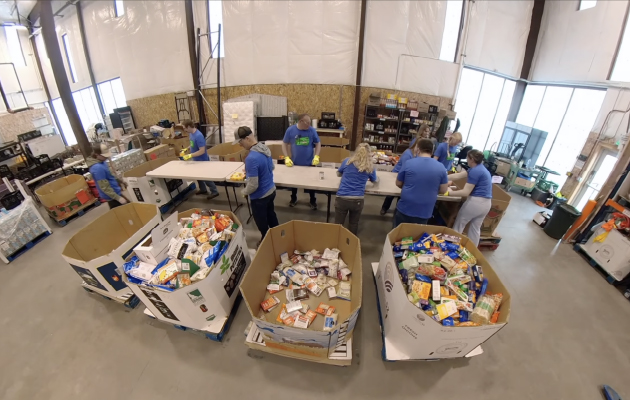 NorthWestern Energy employee volunteers sort donated food and household items at a large donation center.
